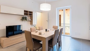 Un espace repas moderne doté d’un téléviseur, d’une table en bois, de chaises et d’un luminaire suspendu.