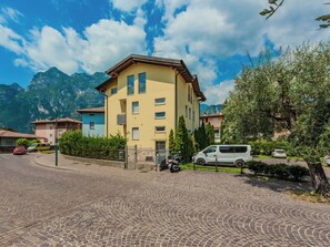 A yellow multi-story building with a paved driveway and a parked scooter. - Lovely apartment for 4 people with WIFI, A/C, TV, patio and panoramic view (Arco)