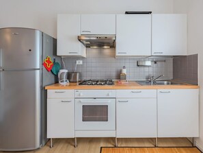 Una cocina moderna con un refrigerador de acero inoxidable, una estufa a gas y armarios blancos.