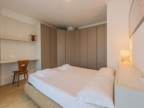 Ein Schlafzimmer mit einem Bett, einem Sessel, einem Nachttisch und eingebauten Schränken.