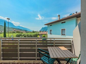 A balcony with a table and chairs, overlooking a mountainous landscape with houses. - Lovely apartment for 4 people with WIFI, A/C, TV, patio and panoramic view (Arco)