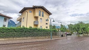 En byggnad med flera våningar, en balkong, en asfalterad gata och ett bergigt landskap i bakgrunden.