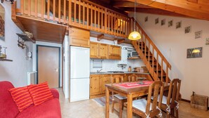 A cozy kitchen with wooden cabinets, a dining table with chairs, and a staircase leading to an upper level. - Cosy apartment for 4 people with WIFI, TV and balcony (Varzo)