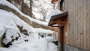 A snow-covered stone wall, wooden building entrance, and a metal gate. - Cosy apartment for 4 people with WIFI, TV and balcony (Varzo)