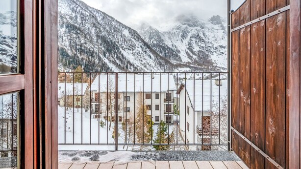 A balcony with a metal railing, a wooden fence, and a view of snow-covered mountains. - Cosy apartment for 4 people with WIFI, TV and balcony (Varzo)