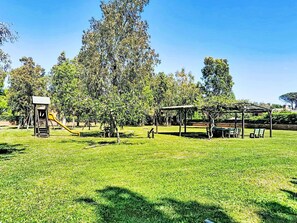 Ein Park mit einem Spielplatz, Picknicktischen und einem überdachten Bereich.