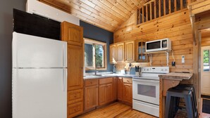 A kitchen with wooden cabinets, a white refrigerator, a microwave, and a stove.