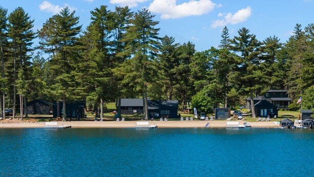 A lakeside property with cabins, a dock, and a sandy beach.