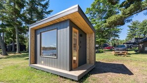 A modern cabin with a large window, a door, and a small porch area.
