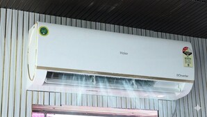Un aire acondicionado blanco instalado en una pared de metal corrugado, con una ventana debajo.