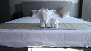 Una cama bien hecha con una colcha blanca y un arreglo decorativo de toallas.
