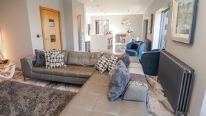 A modern living room with a sectional sofa, a glass coffee table, and a large rug. - Midways (Windermere)