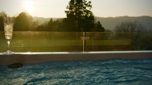 A glass of water on a poolside with a view of a sunset and trees in the background. - Midways (Windermere)