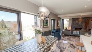 A modern dining area with a patterned tablecloth, a vase with flowers, and a view of the outdoors. - Midways (Windermere)
