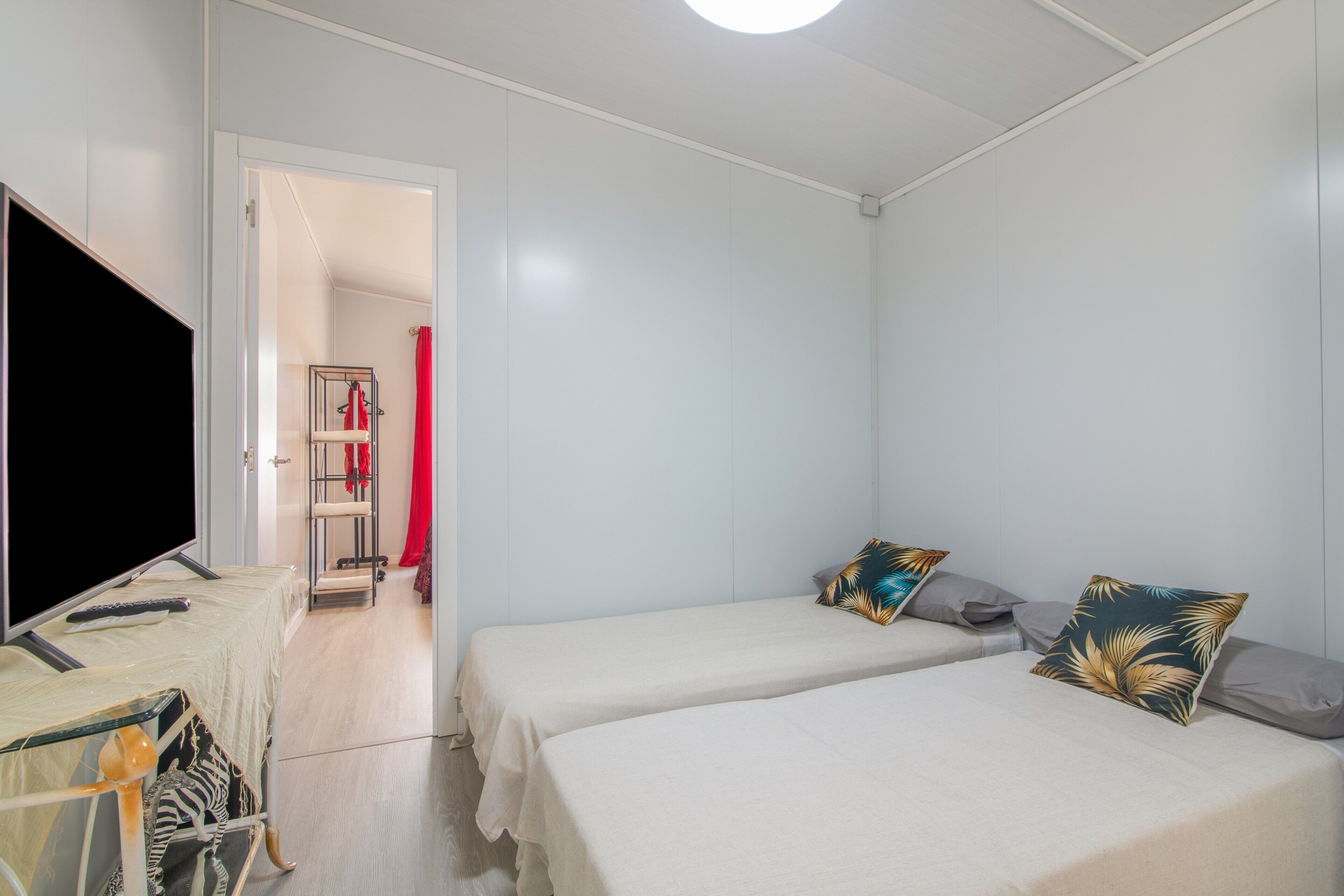 A bedroom with two beds, a TV, and a wardrobe.