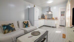 A modern living room with a sofa, a dining table, and a kitchen area with cabinets and appliances. - Apartment 'El Encanto' with Mountain View, Private Pool and Wi-Fi (Villarrasa)