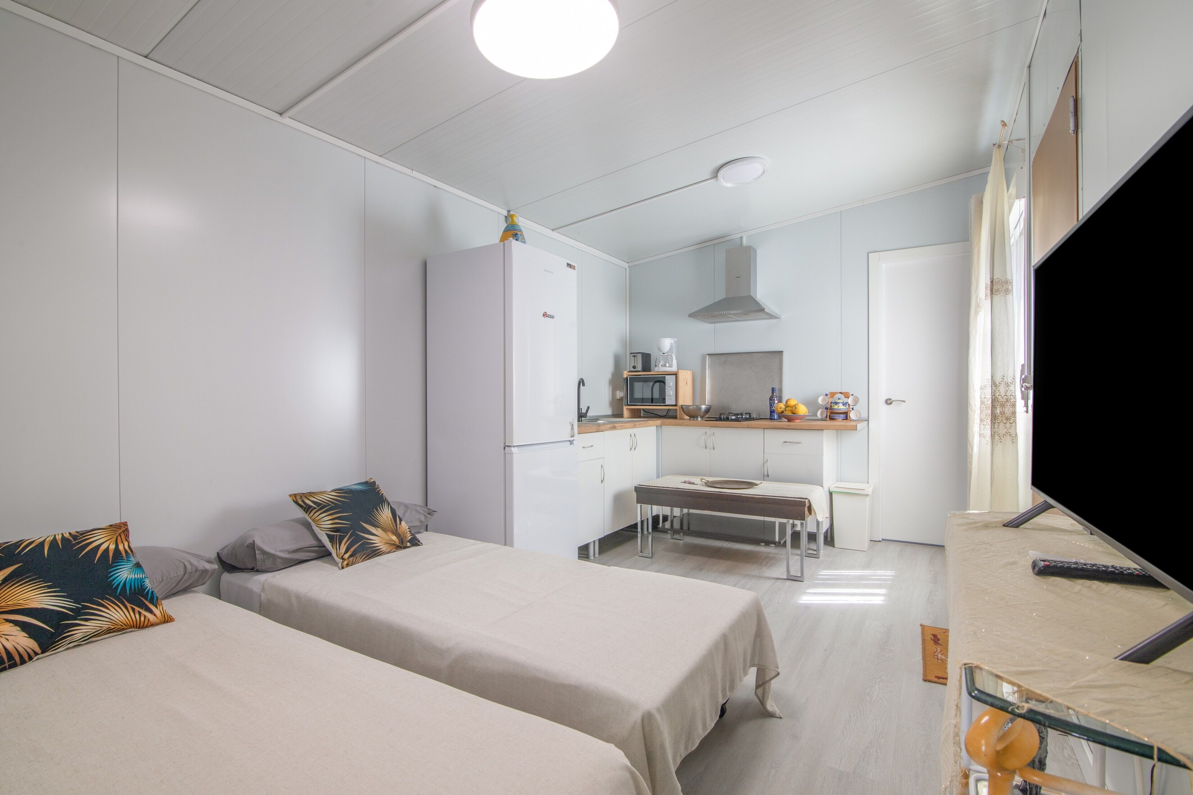 A room with two beds, a kitchenette, a TV, and a bathroom.