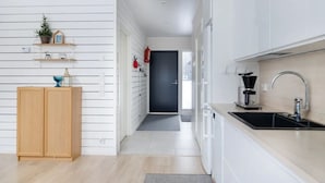 Uma cozinha moderna com armários brancos, uma pia preta e uma máquina de café.
