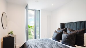 A bedroom with a bed, a dresser, a mirror, and a window with blinds. - 1 Bed City Centre Apt | Sleeps 4 | Juliet Balconies | Long Term Stays Available (Salford)