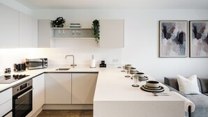 A modern kitchen with a central island, built-in oven, microwave, and sink. - 1 Bed City Centre Apt | Sleeps 4 | Juliet Balconies | Long Term Stays Available (Salford)