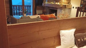 A cozy cabin interior with a wooden cabin structure, a sofa, a white fluffy pillow, and a view of the outside balcony. - Fully renovated duplex with exceptional view of the MONT BLANC (Cordon)