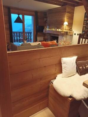 A cozy cabin interior with a wooden cabin structure, a sofa, a white fluffy pillow, and a view of the outside balcony. - Fully renovated duplex with exceptional view of the MONT BLANC (Cordon)