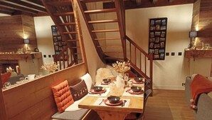 A dining area with a wooden table set for four, a bench with cushions, a staircase, and a wall-mounted photo collage. - Fully renovated duplex with exceptional view of the MONT BLANC (Cordon)