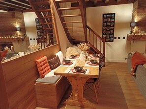 A dining area with a wooden table set for four, a bench with cushions, a staircase, and a wall-mounted photo collage. - Fully renovated duplex with exceptional view of the MONT BLANC (Cordon)