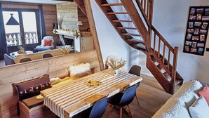 A dining area with a wooden table, blue chairs, and a staircase. - Fully renovated duplex with exceptional view of the MONT BLANC (Cordon)