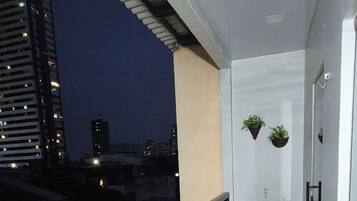 Um corredor com chão de azulejos, pia e plantas penduradas.