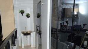 A corridor with a sink, hanging plants, and a glass door leading to a kitchen area. - Apartment in a prime location, quiet and family-friendly environment, close to everything. (Belém)