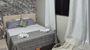 A bedroom with a bed, a smaller bed, a window with curtains, a marble wall, and a ceiling light. - Apartment in a prime location, quiet and family-friendly environment, close to everything. (Belém)
