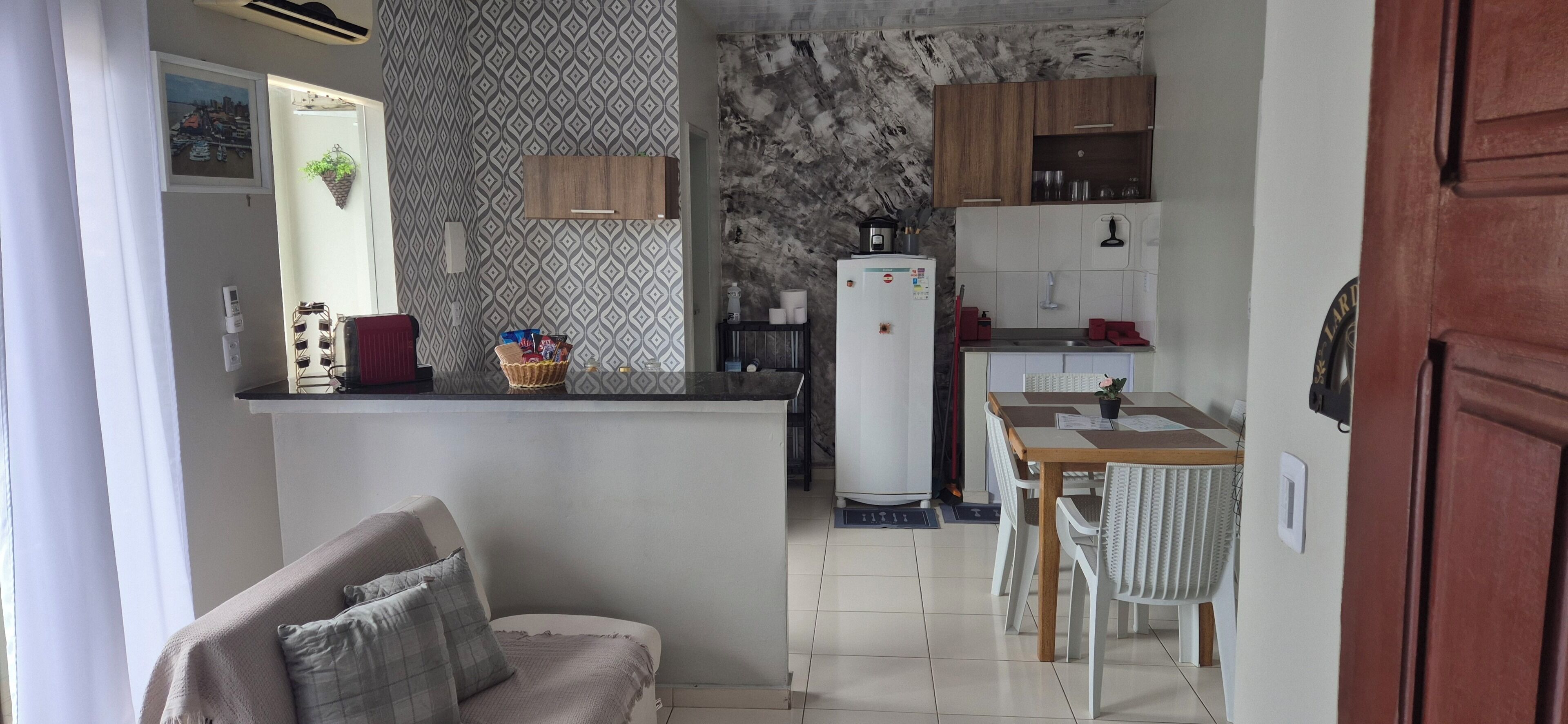 Cozinha compacta com geladeira, fogão e área de refeições.