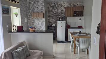 Cozinha compacta com geladeira, fogão e área de refeições.