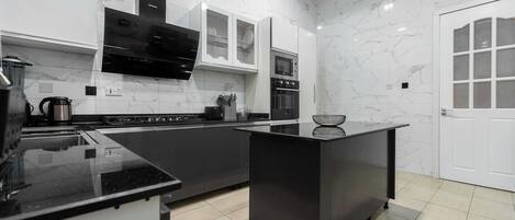 Una cocina moderna con encimeras negras, armarios blancos y horno integrado.