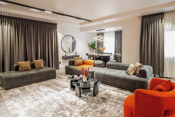 A modern living room with grey sofas, a coffee table, and a bright orange chair.