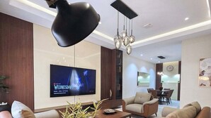 Una sala de estar moderna con dos sofás, una mesita de centro, una lámpara de pie, un televisor y una planta en maceta.
