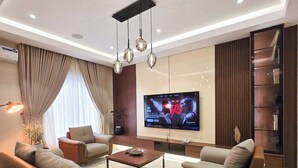 Una sala de estar moderna con un televisor de pantalla plana, sofás de cuero, una mesa de centro y una alfombra estampada.