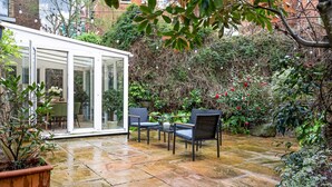 Eine Terrasse mit Glastür, Sitzgelegenheit im Freien und einem Garten.