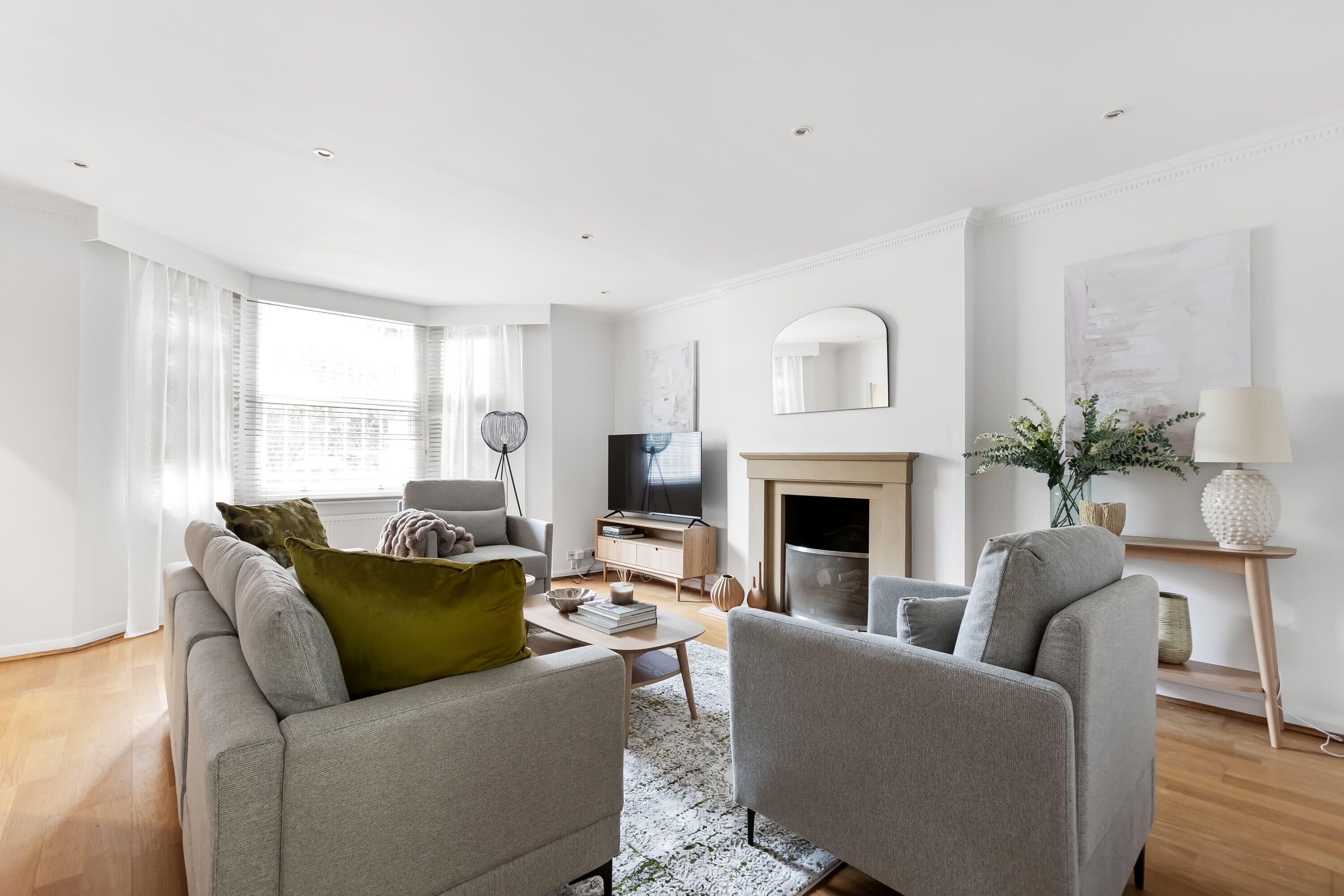 A modern living room with a sofa, armchairs, a coffee table, a television, and a fireplace.