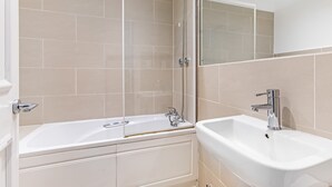 A bathroom with a bathtub, a sink, and a shower. - Stunning Kensington Apartment with Private Garden (Greater London)