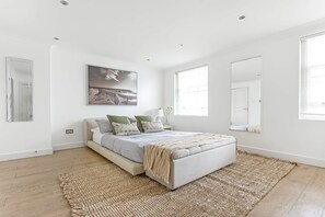 Ein Schlafzimmer mit einem Bett, einem großen Fenster und einem Bild an der Wand.