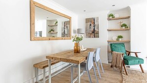 A dining area with a wooden table, metal chairs, a bench, a mirror, and a green chair. - Stunning Kensington Apartment with Private Garden (Greater London)