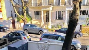 Ein Wohngebiet mit Pflasterterrasse, Baum und geparkten Autos.