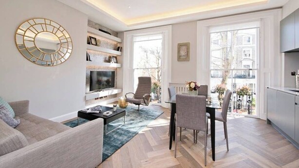 Ein modernes Wohnzimmer mit einer Couch, einem Couchtisch, einem Fernseher und einem Essbereich mit Stühlen und einem Tisch.