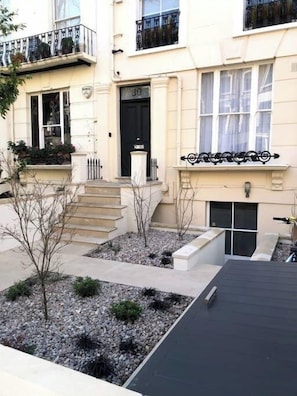 A two-story building with a black door, numbered 39, and a small garden area with gravel and plants. - Notting Hill | Beautiful Design | High Ceilings | (London)