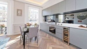 Eine moderne Küche mit grauen Schränken, einer weißen Arbeitsplatte und einem eingebauten Backofen.