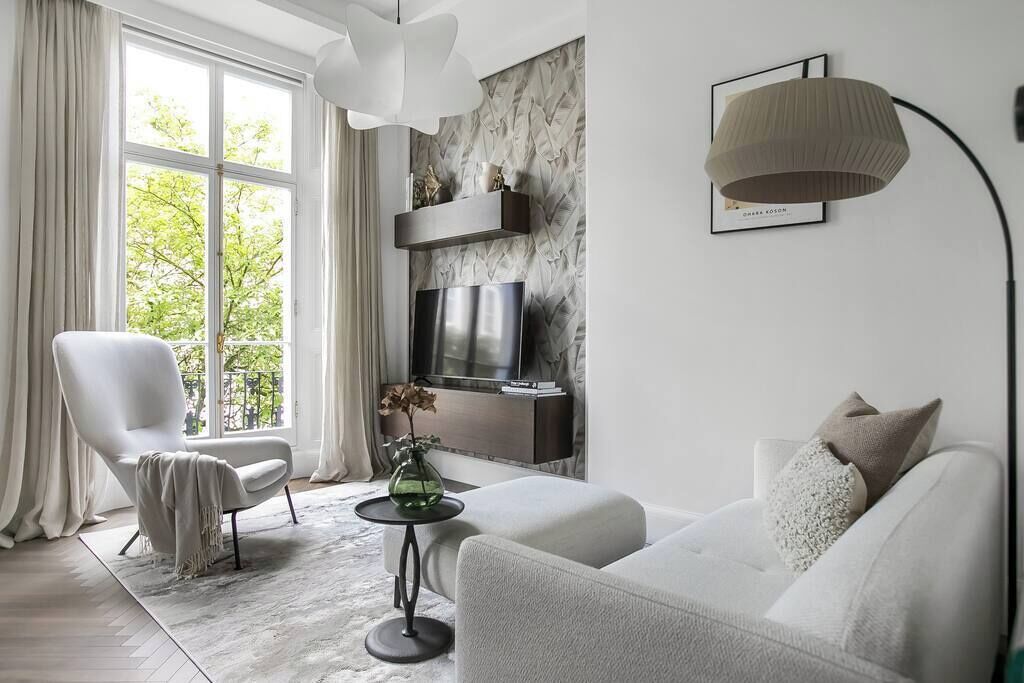 Una sala de estar moderna con un sofá, un sillón, televisión y objetos decorativos.