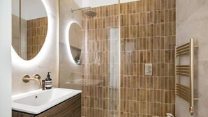 A modern bathroom with a large mirror, a sink, a shower, and a towel rack.