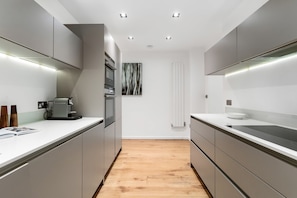 A modern kitchen with built-in appliances, a coffee machine, and a minimalist design. - Large Notting Hill Flat with Garden (Greater London)